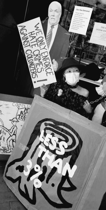 Me with face mask & fedora hat on. Chained to entrance of BC Ministry of Environment building. Standup of ecocidal maniac John Horgan & other environmental protest signs surround me.
Monochrome photo.