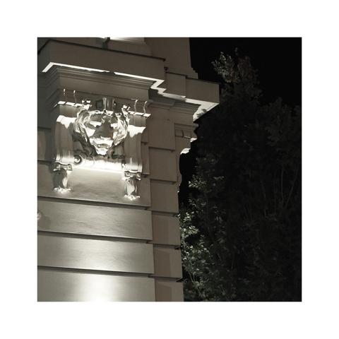 Iron

A relief of a lion's head on an engaged column is lighted from below. In the background, behind the corner, there are green trees hidden in darkness.

---

Bratislava, Old Town, the 8th of October 2023