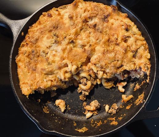 Cast iron frypan with half a baked mac and cheese with beef
