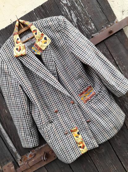 A blazer wirh small checks in dark green, beige and bright lilac on white with patches of a southern French print with roosters and flowers. The collar is repaired with the fabric, still 2 patches to fix.