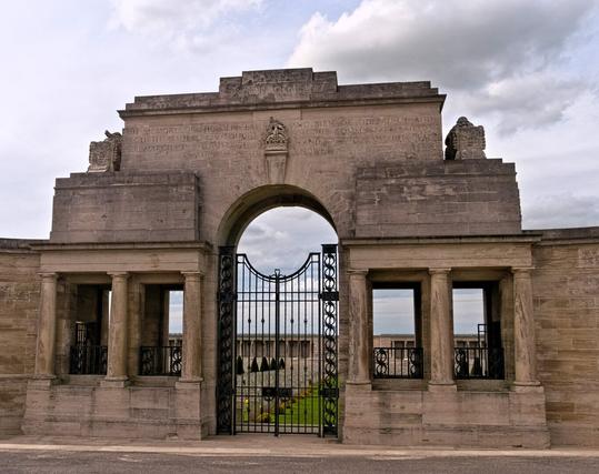 The entrance to the memorial. The entire site is an open arcade terminated by small buildings and broken in the middle by the entrance archway and gates.