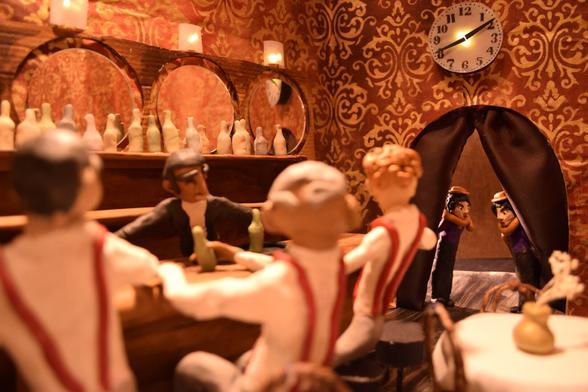 A stop-motion set of a jazz club with three claymation characters sitting at a bar, a bartender behind the bar, and a pair of twins in the doorway