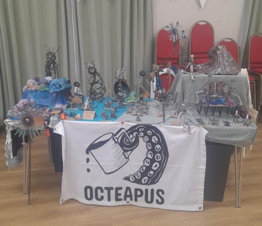 OcTeaPus stall, a table with lots of metal work on plus crocheted octopuses in a village hall