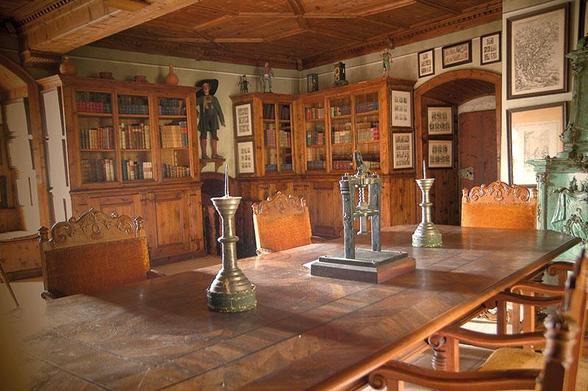 a photo of a dining hall type area, some bookcases and lots of cool old pictures on the wall