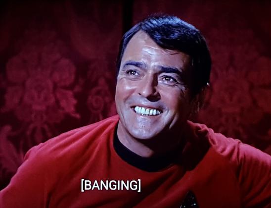 Star Trek The Original Series scene. Montgomery Scott, in his red uniform and with a floral red velvety looking backdrop, looks happy. Like, just SO happy. He's beaming, not StarTrek beaming, just happy beaming. Closed caption reads: [BANGING]