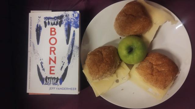A plate with three wholemeal rolls and cheese and an apple, next to a copy of Borne by Jeff VanderMeer