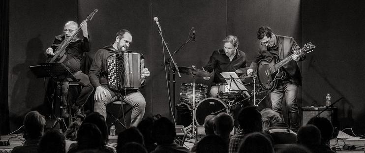 De gauche à droite sur scène, Christian à la basse, Frédéric à l'accordéon, Cédric à la batterie et aux percussions, Filipe à la guitare (photo en noir et blanc)