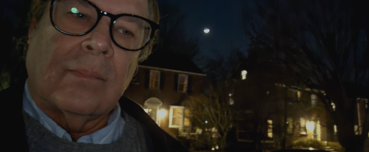 @KronoMoon photo at night on March 02, 2025, 8pm EST. This is 12 nights before the Full Moon and the Total Lunar Eclipse. Left side of frame is a closeup of a serious looking Community Time Travel Researcher wearing glasses and gazing slightly off-camera. Behind him is a row of 2-storey mid-century brick homes with a few trees. 

Between the homes and over his left shoulder is a first glimpse of a crescent Moon, in soft focus. March's Moon is the Worm Moon. On March 14 at 07:00 UTC, less than 2 weeks away, will be the Full Moon, and a Total Lunar Eclipse.  That's when Time Travelers are invited to make contact. Join us outside under the Total Lunar Eclipse!  

🔗 https://KronoMoon.org 🏳️‍🌈 ☮️
#KronoWatch