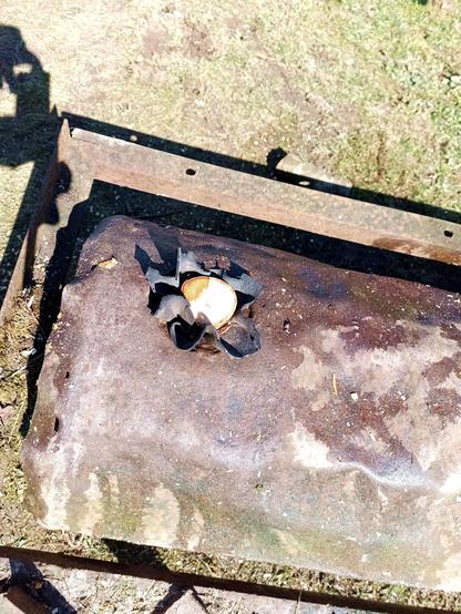The roller again, now filled with water, some of which has spilled over it. A wooden bung is hammered into the hole surrounded by some black rubber material bunching up around it. The bung has been cut down to be flush with the roller drum.