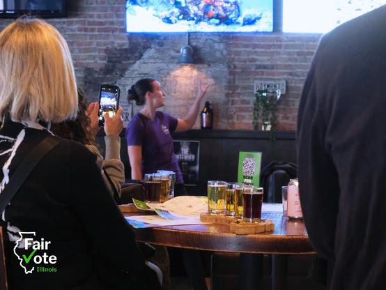 FairVote Illinois Statewide Organizer Rebecca Williams presents on ranked choice voting at a bar in Chicago.