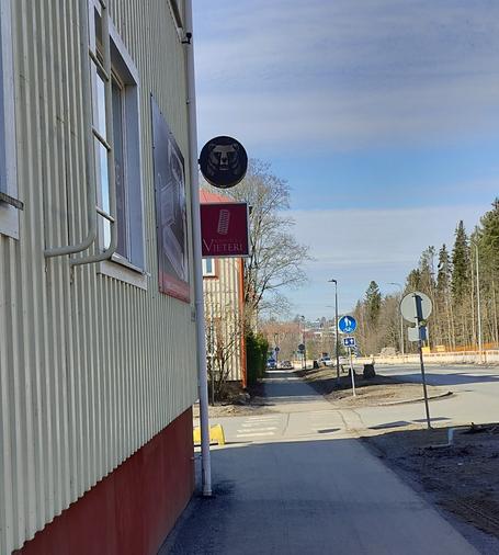 Katu, jonka varrella puutaloja. Yhden talon seinässä kyltti "Vieteri",  jossa myös vieterin kuva. Sen yllä Karhu-oluen mainoskyltti.