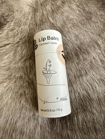 Photo 2
A closeup shot of my cardboard tube of natural lip balm, resting on the luscious fur of Doots, a Lynx Point Siamese cat, mimicking the setup from photo 1.