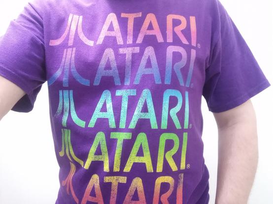 A picture of the t-shirt I'm wearing today. It has a stack of Atari logos followed by the word Atari all the way from the neck to the bottom of the shirt. The logos and the wording are colored following a rainbow pattern over the dark purple color of the shirt.