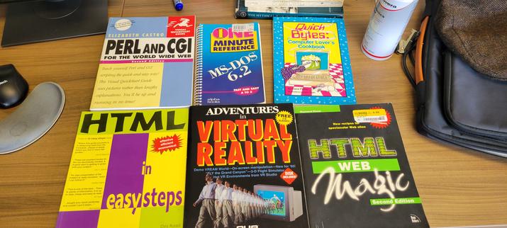 6 books laying on a desk. From top left to bottom right, they are: 
Perl and CGI, For The World Wide Web
One Minute Reference: MS-DOS 6.2
Quick Bytes: Computer Lover's Cookbook
HTML In Easy Steps
Adventures In Virtual Reality
HTML Web Magic