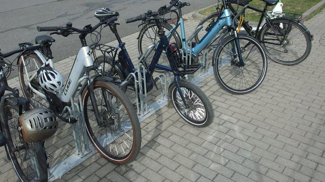 Five bicycles parked in a front wheel bike rack. All bikes are parked next to the front wheel ›input‹, none did actually place their front wheel in it.