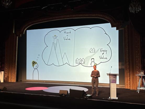 Felienne presents a slide with a cartoon picture of herself, with a thought bubble that visualises the bias that "hard = value" and "easy != value" through the metaphor of the fact that we know more about remote glaciers high up in mountains than about glaciers that are right next to where people live.