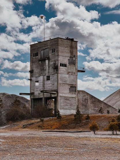 En stor hög koloss i betong som var en del i kalkstensindustrin på 1970-talet. Nu till synes övergiven bland stora högar av kalksten och sand i ett månlikt landskap under en molnig himmel.