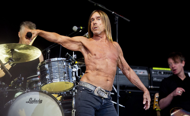 A recent photo of a shirtless Iggy Pop in concert. Behind him is a drummer playing a Ludwig drum kit and another band made.