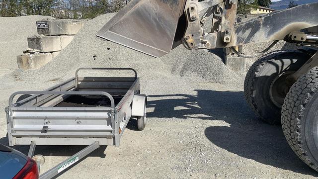 A large bulldozer dumps stone into the trailer