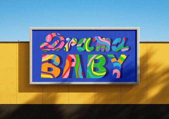 A billboard on a yellow wall displays the words "Drama BABY" in bold, colorful, abstract letters against a blue background.