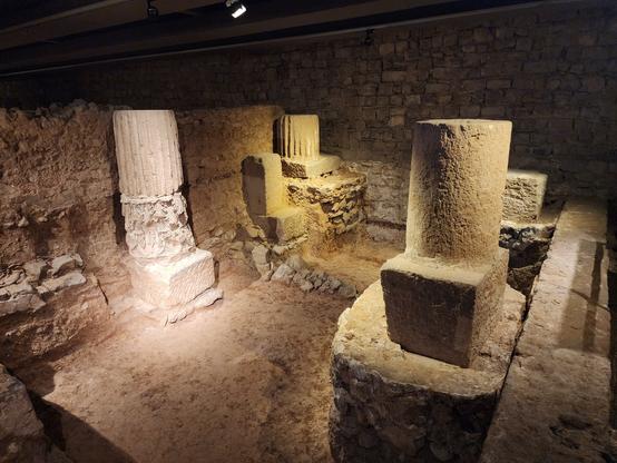 Underground display of archaeological site. Remnants of four pillars about 5ft tall.
