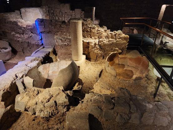 underground exhibit of remnants of Roman Barcelona, with foundation walls and the bottom halves of two spherical containers about 1.5 meters in diameter.