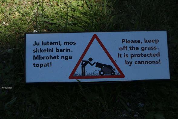 A sing saying "please keep of the grass, it is protected by cannons!