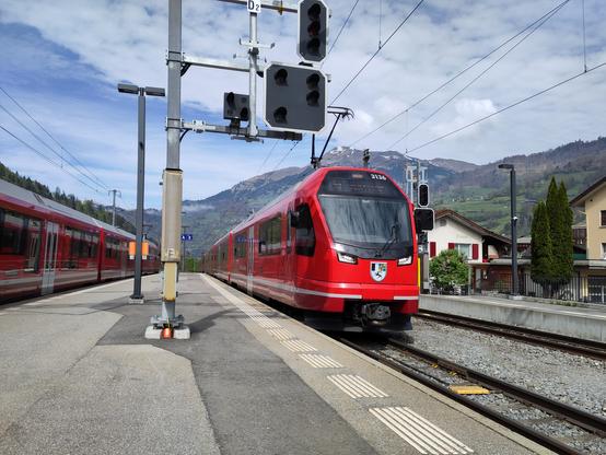 Foto. Zwei rote Züge im Bahnhof.