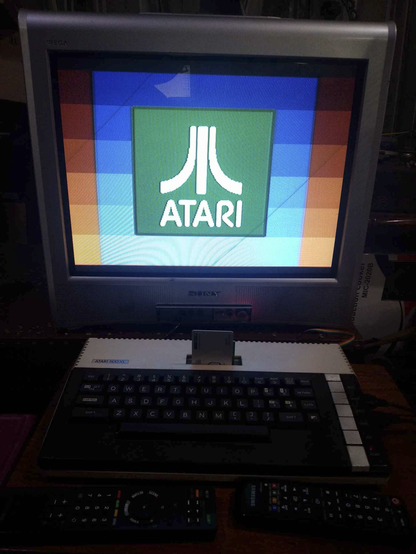 An Atari 800XL computer connected to a Sony flatscreen TV, with the Atari logo on a green square, on a blue layered square and a red layered square displayed on screen.