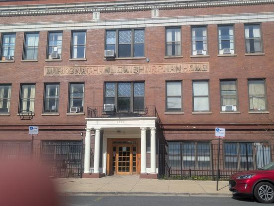 Photo of a large, old brick building with an enormous block of carved stone that says MARKSNATHANJEWISHORPHANHOME