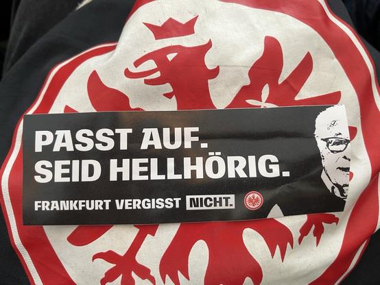 Sticker mit Konterfei von Sonny Sonneberg und dem Text: PASST AUF. SEID HELLHÖRIG. FRANKFURT VERGISST NICHT.