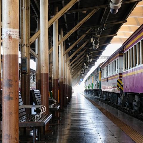 color photo taken at the Bangkok train station of a parked train along a passenger platform built in early 20th century