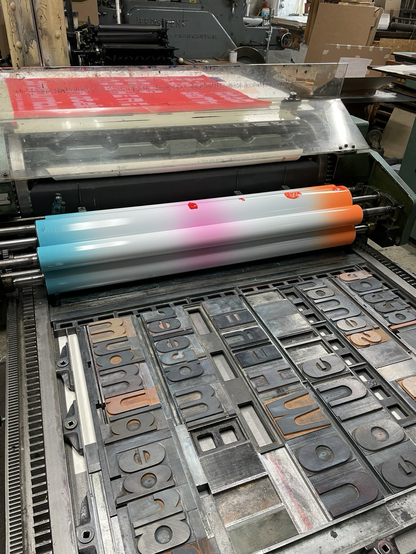 Handsatz mit Holzlettern auf einer Andruckpresse für den Druck eines Plakats. Dritten Druckgang mit Farbverlauf Orange-weiß-Pink-Weiß-Türkis