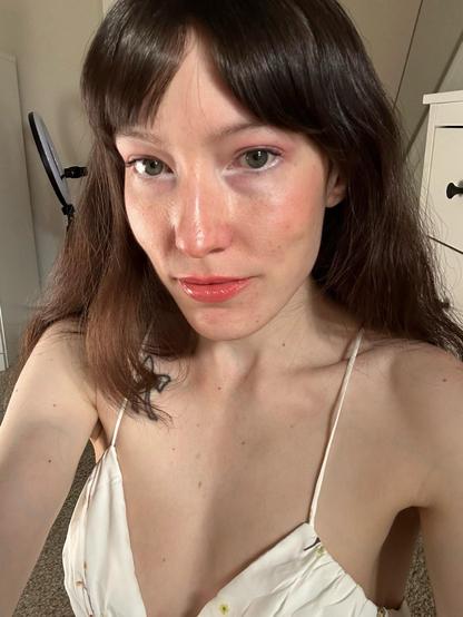 Selfie of me, white femme with dark brown hair, wearing a white floral spaghetti strap dress