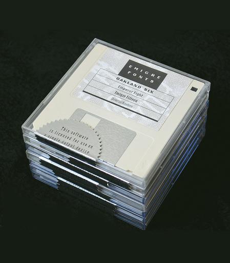A stack of white floppy disks in clear cases. The top disk has a label with “Emigre Fonts: Oakland Six, Emperor Eight, Emigre Fifteen, Universal Nineteen”. A silver sunburst sticker is wrapped around the bottom of the disk. The visible upper half reads, “This software is licensed for use on a single output device”.
