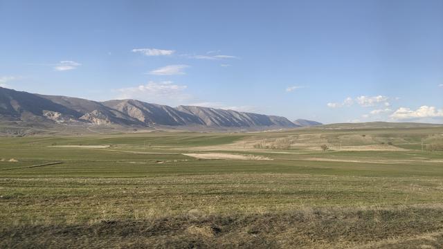 Wide grass grounds with high mountains in background.