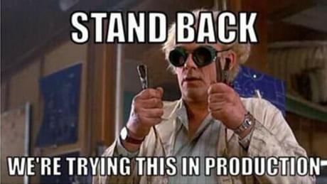 Doc, Back to the Future, holding starter cables. Has the text:
Stand back
We're trying this in production