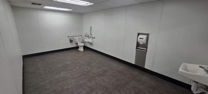 A bathroom but the room is very long with a toilet at one end, sink at the other. Tower dryer in the middle on the wall.