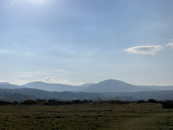 A blue sky with a few clouds; a broad landscape of hills