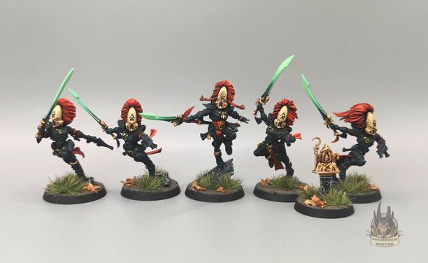 5 Howling Banshee aspect warriors including an Exarch, all in  black armour with ivory helmets and green bladed swords, with red as the accent colour on the plumes and cloth
