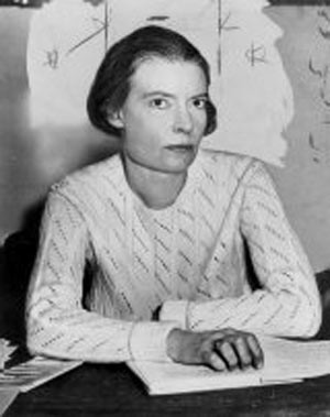 Day in 1916, with short hair, looking at the camera, telephone in the background. By Unknown photographer - http://www.corbisimages.com/stock-photo/rights-managed/BE064360/dorothy-day?popup=1, Public Domain, https://commons.wikimedia.org/w/index.php?curid=71647416