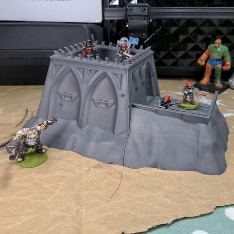 A grey plastic model sci-fi bunker surrounded by painted imperial guardsmen on a messy desk