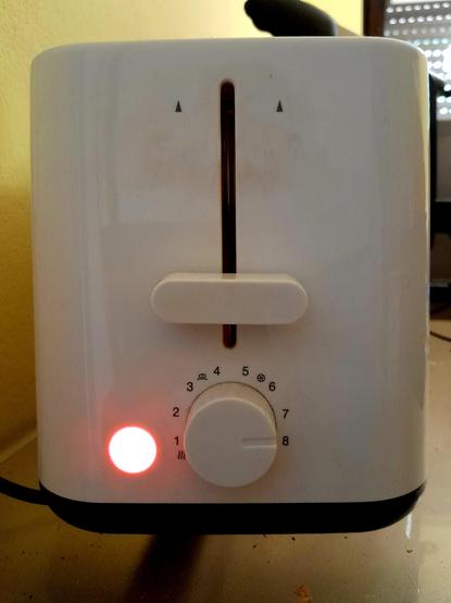 Toast is in the toaster, round side down. The handle is down, the light on. Now I wait.