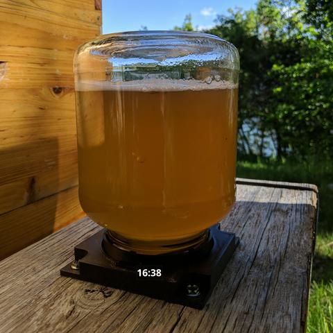 A photo showing a larger feeder jar set on the fixture. The time shows 16:38. The feeder contains 660 grams of honey and 660 grams of water. There is about an inch or 25mm space in the top of the jar.