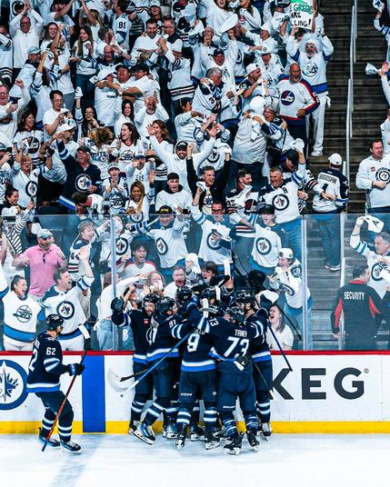 Photo of the Winnipeg Jets in a their home uniforms celebrating the win in front of their crowd.