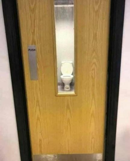 Door with window looking right into a toilet stall