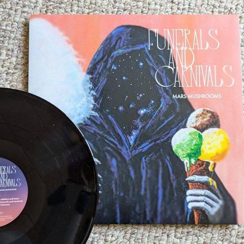 Eine Vinyl-Schallplatte mit einer schwarzen Scheibe neben dem farbenfrohen Albumcover mit dem Titel "Funerals and Carnivals" von Mars Mushrooms. Das Cover zeigt eine Figur in dunklen Gewändern, die Eistüten in verschiedenen Farben hält, vor einem zartrosa Hintergrund.