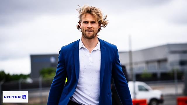 Jakob Chychrun prepares to board the team plane wearing a bright blue suit.