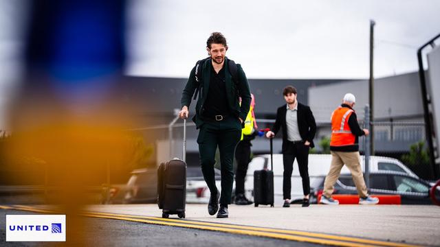 Brandon Duhaime wheels his suitcase across the tarmac.
