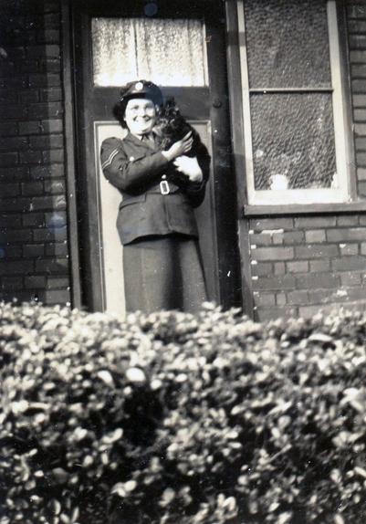Joan in ATS uniform standing at her front door holding Twaddles the cat, taken in 1945